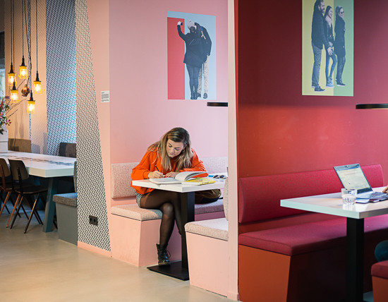 Woman does work in a pink private booth in the lobby of The Student Hotel Amsterdam West