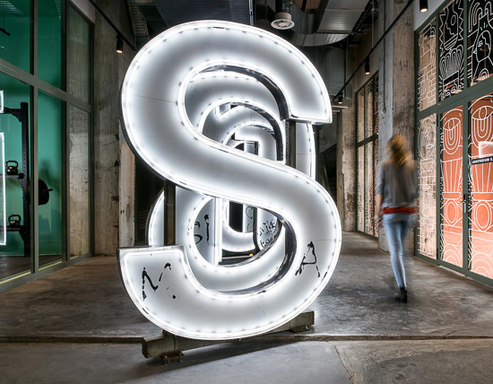 Woman walks past a row of giant illuminated letters at The Student Hotel Maastricht