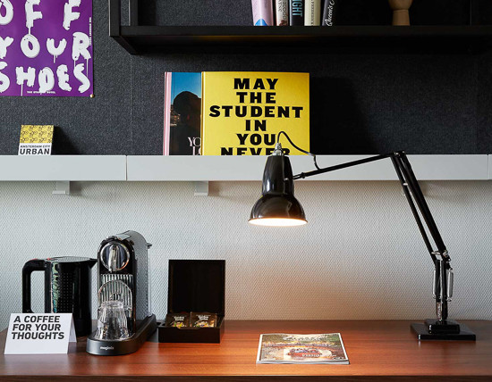 Close up of desk with coffee machine and lamp in a guest room at The Student Hotel Vienna